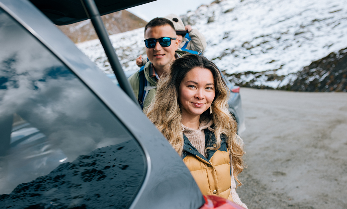 A woman and man stand near a car