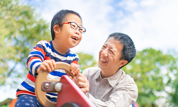 A dad playing at the park with his son.