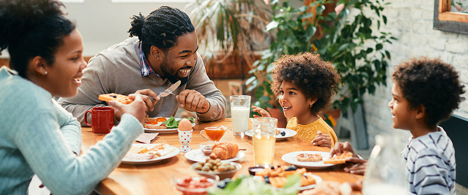 A family sitting at a table eating dinner and talking 