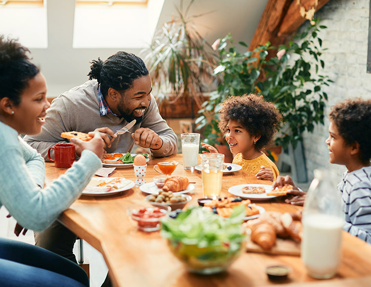 A family sitting at a table eating dinner and talking 