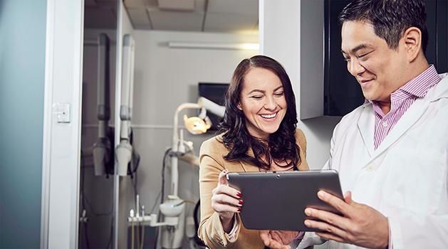 A dentist and patient looking at an iPad